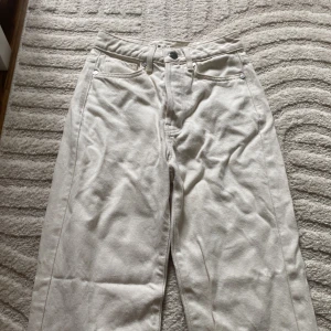 Vita wide leg jeansbyxor - Säljer ett par vita jeansbyxor med regular wide passform och klassiska fem fickor. Byxorna har hög midja och raka, vida ben. Skitsnygga och endast använda en gång men tyvärr är dom för små för mig