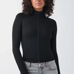 Svart figurnära tröja med dragkedja - Säljer en svart, figurnära tröja med hög krage och hel dragkedja framtill. Perfekt för en stilren och sportig look går även å gymma med 