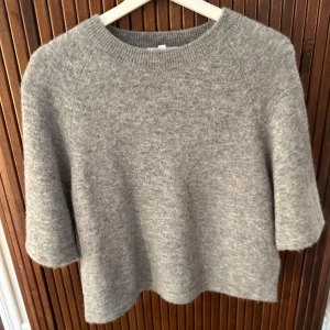 Grå stickad tröja från & Other Stories - Mysig grå stickad tröja från & Other Stories med rund halsringning och trekvartsärmar. Perfekt för lager-på-lager och enkel att matcha med olika outfits.