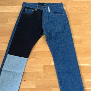 Gosha Rubchinskiy navy Levis edition 501 patchwork jeans - Unika Levis 501 patchwork jeans i samarbete med Gosha Rubchinskiy. Byxorna har en mix av blå denim, svart och ljusblå patch på vänster ben samt svart bakficka. Klassisk rak passform och knappgylf. Oanvända tyvärr medföljer inget förutom byxorna