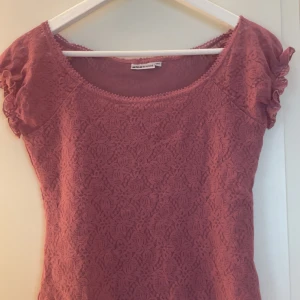 Rosa spetsblus från Gina Tricot - Säljer en söt rosa blus från Gina Tricot i storlek M. Toppen har korta puffärmar och är helt täckt av ett fint spetsmönster. Perfekt för dig som gillar romantisk stil och vill ha något extra till garderoben.