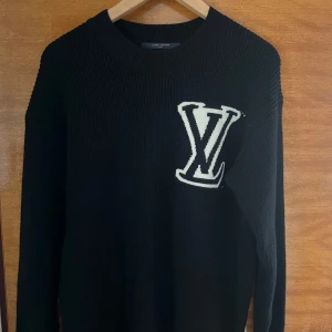 Svart stickad tröja från Louis Vuitton - Säljer en svart stickad tröja från Louis Vuitton med stort vitt LV-logotyp på bröstet. Tröjan har rund halsringning och långa ärmar. Perfekt för dig som vill ha en stilren och exklusiv look. Priset kan diskuteras vid snabb affär. Använd 1 gång men är för stor för mig.