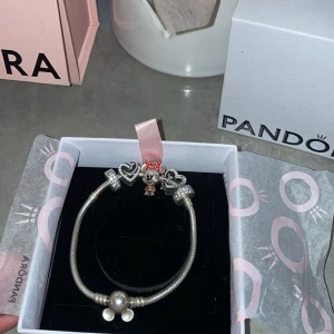 Pandora armband med Minnie Mouse och hjärtan - Snyggt silverfärgat Pandora armband med flera berlocker, bland annat en gullig Minnie Mouse med rödprickig rosett och klänning, samt två hjärtformade berlocker och glittriga detaljer. Perfekt för dig som älskar Disney och vill ha något personligt på handleden. Har aldrig använt de och priset kan diskuteras fick den nyss i 18 år present gillar inte silver de är därför jag säljer det💕💕