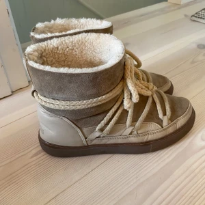 Bruna vinterboots från Inuikii - INTRESSEKOLL! Ett par snygga och varma vinterboots från Inuikii. De är i en fin beige/brun färg med en mysig pälsfodring på insidan. Skorna har spruckit lite i lädret (se sista bilden) nypris är 2999 kr. 