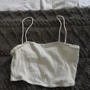 Vit ribbad linnetopp från SHEIN - Fräsch vit linnetopp från SHEIN i storlek XS. Toppen har tunna axelband och är ribbad för en snygg och trendig look. Perfekt att matcha med jeans eller kjol för en chill stil. Materialet är mjukt och stretchigt, vilket gör den skön att bära under varma dagar.