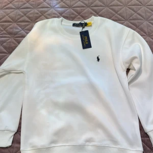 Vit sweatshirt från Polo Ralph Lauren - Säljer en stilren vit sweatshirt från Polo Ralph Lauren med klassisk rund hals och svart broderad logga på bröstet. . Helt ny pris kan diskuteras 