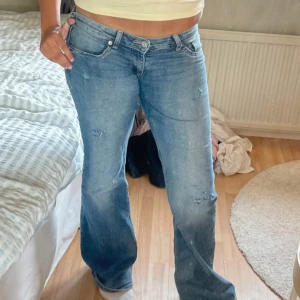 Blå bootcut jeans låg midja - Snygga blå jeans med bootcut passform och låg midja. Jeansen har klassisk femficksdesign och lätt slitna detaljer för en cool vibe. Perfekt för dig som gillar avslappnad stil med lite edge.