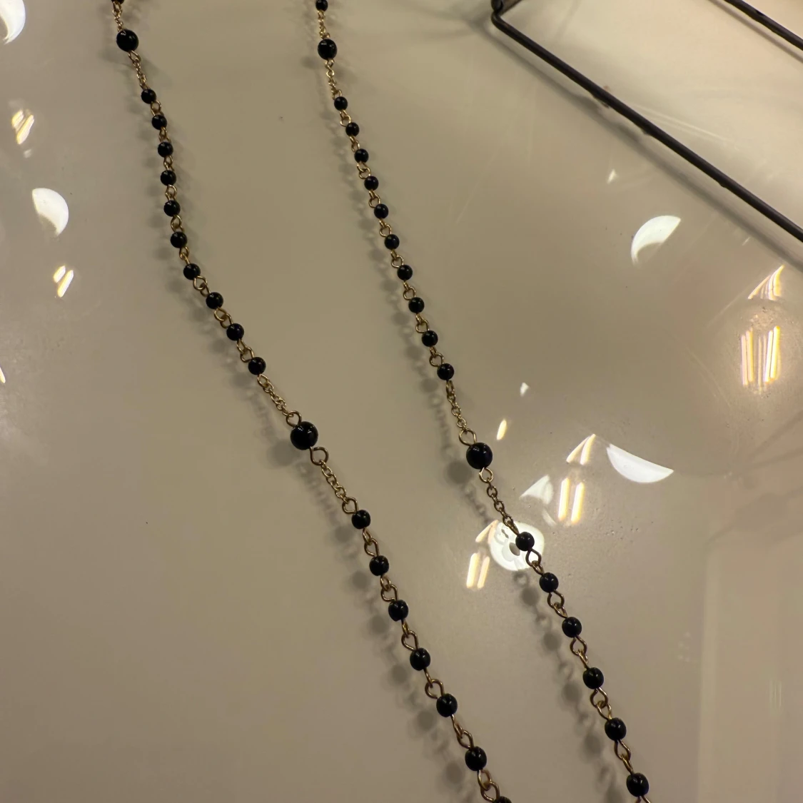 Guldigt halsband med svarta pärlor och berlocker - 1