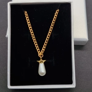 Guldhalsband med pärlhänge - Stilrent halsband i guldton med en kedja och ett droppformat vitt pärlhänge som har en liten guldfärgad detalj upptill. Perfekt för dig som gillar klassiska smycken med en modern twist. Kedjan har ett smidigt lås och hängsmycket ger en elegant vibe.