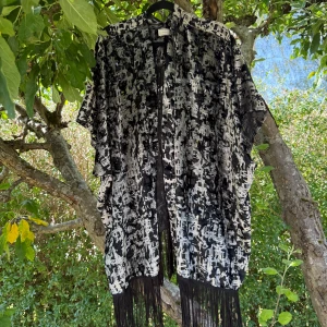 Svart och grå mönstrad väst från Cream - Säljer en luftig väst/ poncho från Cream i svart och grått med abstrakt mönster. Västen har öppen front, vida ärmhål och långa fransar längs nederkanten. Materialet är mjukt och lätt, perfekt för lager-på-lager och en cool boho-look. Mycket fint skick, jag hittar inga synliga anmärkningar eller defekter. Tyget är lite sammet/ velour likande. 