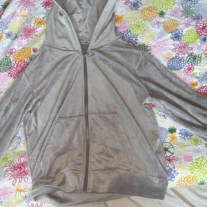 Beige velour hoodie med dragkedja - Säljer en beige hoodie i mjuk velour med hel dragkedja och stor huva. Tröjan har långa ärmar och en praktisk känguruficka framtill. Perfekt för chill dagar och när du vill ha något riktigt comfy på dig.