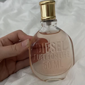 Diesel Fuel For Life 50ml parfym - Diesel Fuel For Life parfym i 50ml flaska. Flaskan är transparent med en lätt rosa tonad vätska och har en snygg guldfärgad kork. Texten är ingraverad direkt på glaset vilket ger en cool och modern känsla.
