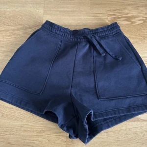 Mörkblå shorts från Dobber(MQ) XS | Nypris 299 - Snygga mörkblå shorts från Dobber i mjuk bomull. Modellen har hög midja, bred resår och snörning i midjan för skön passform. Stora fickor framtill ger en chill vibe. Perfekta för sommarens häng eller träning. Nyskick, aldrig använda. Utan prislapp