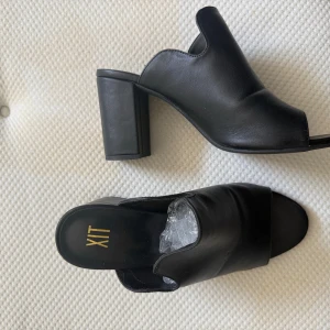 Svarta klackade sandaler från XIT - Använt enstaka gång. Snygga svarta sandaler från XIT med bred klack och öppen tå. Skorna har en stilren design i slätt skinnmaterial och en bekväm plattformsula. Perfekta för dig som gillar minimalistisk stil och vill ha något som sticker ut med chunky klack.