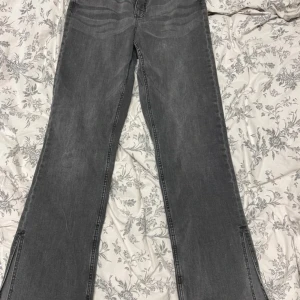 Grå wide jeans med slits från Denim - Säljer ett par gråa jeans från Denim med breda ben och snygga slitsar längst ner. Modellen är high waist och har klassiska fem fickor samt dragkedja och knapp framtill. Perfekt för dig som gillar en chill och trendig look. Storleken står inte men de är nog M/L ungefär 