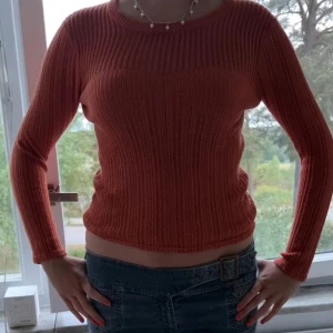 Ribbad orange stickad tröja - Säljer en snygg ribbad stickad tröja i orange med rund hals och långa ärmar. Tröjan har en slim passform och är perfekt för dig som gillar färg och vill ha något som sticker ut. 