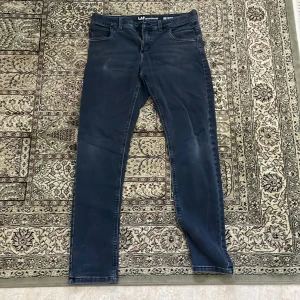 Mörkblå slim fit jeans från LAB - Snygga mörkblå jeans från LAB Industries i slim fit-modell. Klassisk femficksdesign, normalhög midja och diskreta slitningar för en modern look. Jeansen är tillverkade i stretchigt material som ger en skön passform och stilren vibe.