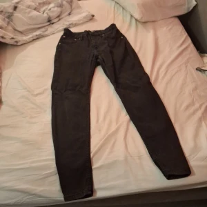 Svarta lager skinny jeans - Säljer ett par svarta lager 150 jeans i storlek L. De har en skinny passform med klassisk femficksdesign och snygga nitar vid fickorna. Jeansen är gjorda i stretchigt denim som sitter tajt och bekvämt hela dagen. Perfekt för dig som gillar en smal siluett.
