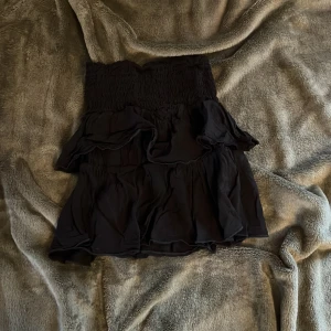 Svart volangkjol  - Supersnygg svart volangkjol i storlek 134/140.Kjolen är lätt och luftig, perfekt att använda för att stylea sommar outfits. Kjolen är mycket stretchig.💕