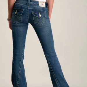 W25 True Religion jeans - Snygga blå jeans från True Religion med bootcut passform och klassiska fickor med gul kontrastsöm och knappdetaljer bak. Jeansen har låg midja och är tillverkade i mjukt denimtyg som sitter skönt. Jeansen är uppsydda ungefär 5 cm men passar jättebra på mig som är 157 cm lång.  Dessutom är jeansen helt oanvända!!!💖💖