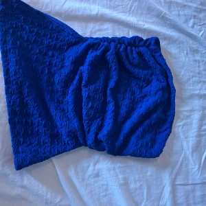 Blå tub topp  med struktur - Säljer en cool blå tub topp  med elastisk midja och snyggt strukturerat tyg. Tröjan har en unik form med draperad effekt och känns riktigt trendig. Perfekt för dig som vill sticka ut med färg och textur. Passar dig som gillar att experimentera med din stil.