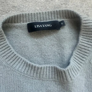 Grå kashmirtröja från Lisa Yang - Supermjuk och lyxig grå tröja från Lisa Yang i 100% kashmir. Rund hals och ribbade muddar vid ärmslut och nederkant. Perfekt för dig som gillar stilrena och sköna plagg med premiumkänsla. Passar dig som vill ha en klassisk look med extra komfort.