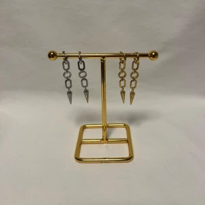 Chunky kedjeörhängen med spikes - Två par örhängen med chunky kedjor och spetsiga spikes i metall. Ena paret är i silverfärg och det andra i guld, båda har coola länkar och hängande konformade detaljer. Perfekt för dig som gillar edgy och statement smycken.