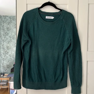 Långärmad tröja Size 8 Needle - Mörkgrön långärmad tröja från Size 8 Needle. Tunnt stickad med ett ”pärlat” mönster på ärmar och rygg. Storlek: M. Material: 60% bomull, 40% akryl. I använt skick, men inga skador. 