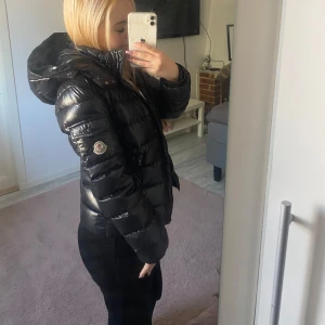 Svart Moncler pufferjacka med huva - Säljer en svart moncler jacka i storlek xxs, barnstolen 12 år, den är använd men fortfarande jätte fin säljer för den är förliten för mig, märket inuti jackan har gått sönder men man får me klistermärket så de går att sy fast om man vill de igen  