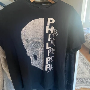 Svart Philipp Plein t-shirt med strass - Hejsan! Jag säljer en svart T-shirt från Philipp plein. Storlek xl men skulle säga att den är liten i storleken🥰 ball tröja som passar både tjejer och killar! Den är i fantastiskt skick. Pris kan absolut diskuteras så skriv vid frågor!