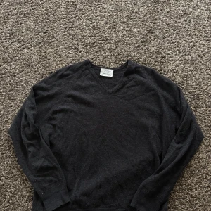 Svart v-ringad merinotröja Glenbrae - Svart v-ringad tröja från Glenbrae i mjuk och tunn merinoull. Klassisk och enkel design med långa ärmar och ribbade muddar vid ärmslut och nederkant. Perfekt för dig som gillar stilrena och bekväma plagg med lite lyxig känsla.