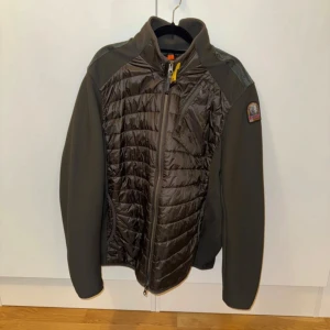 Grön pufferjacka från Parajumpers - Snygg grön pufferjacka från Parajumpers med quiltad framsida och rygg, samt släta ärmar. Jackan har dragkedja framtill, ståkrage och en patch på ena ärmen. Materialmix med polyester och syntet, perfekt för kyliga dagar. Stilren design med sportig känsla.