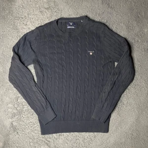 Gant tröja  - Säljer en stilren marinblå kabelstickad tröja från GANT i premium bomull. Tröjan har en klassisk rund halsringning och långa ärmar. Perfekt för en elegant och avslappnad look. 🖤