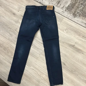 Mörkblå jeans från Replay (ANBASS) - Snygga mörkblå jeans från Replay med klassisk femficksdesign och en bekväm passform. Jeansen har en diskret tvätt för en modern look och är perfekta för en stilren vardagsstil. 