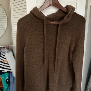 Brun stickad hoodie från Noisy May - Mysig brun stickad hoodie från Noisy May. Perfekt för kyliga dagar med sin mjuka och bekväma passform. Den har en klassisk huva med dragsko och långa ärmar. En stilren och enkel design som passar till det mesta.