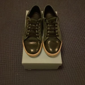 Sneakers från Lanvin - Snygga sneakers från Lanvin med en stilren design. Skorna har en blank tå och snörning där fram. Lådan följer med. Skorna är i storlek UK 9 men passar både 43 och 44. 1100 kr om skorna köps idag fredag.