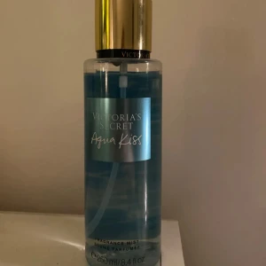 Aqua Kiss Fragrance Mist från Victoria's Secret - Fräsch och uppfriskande doftmist från Victoria's Secret, Aqua Kiss. Flaskan är genomskinlig med blå vätska och har en elegant guldfärgad kork. Perfekt för en daglig doftuppfräschning. 250 ml, sällan använd!!