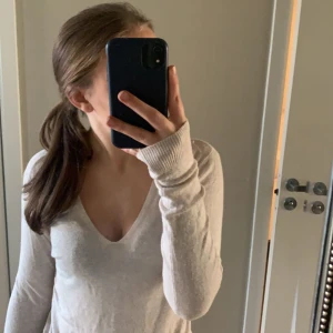 Beige v-ringad tröja - Säljer en stilren beige tröja med v-ringning. Tröjan har långa ärmar och är perfekt för en avslappnad look. Passar bra till jeans eller kjol.