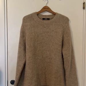 Beige stickad tröja från Bik Bok - Mysig beige stickad tröja från Bik Bok. Perfekt för kyliga dagar med sin mjuka och varma känsla. Tröjan har en rund halsringning och långa ärmar, vilket gör den till ett stilrent val för höst och vinter eller en kylig sommarkväll🥰