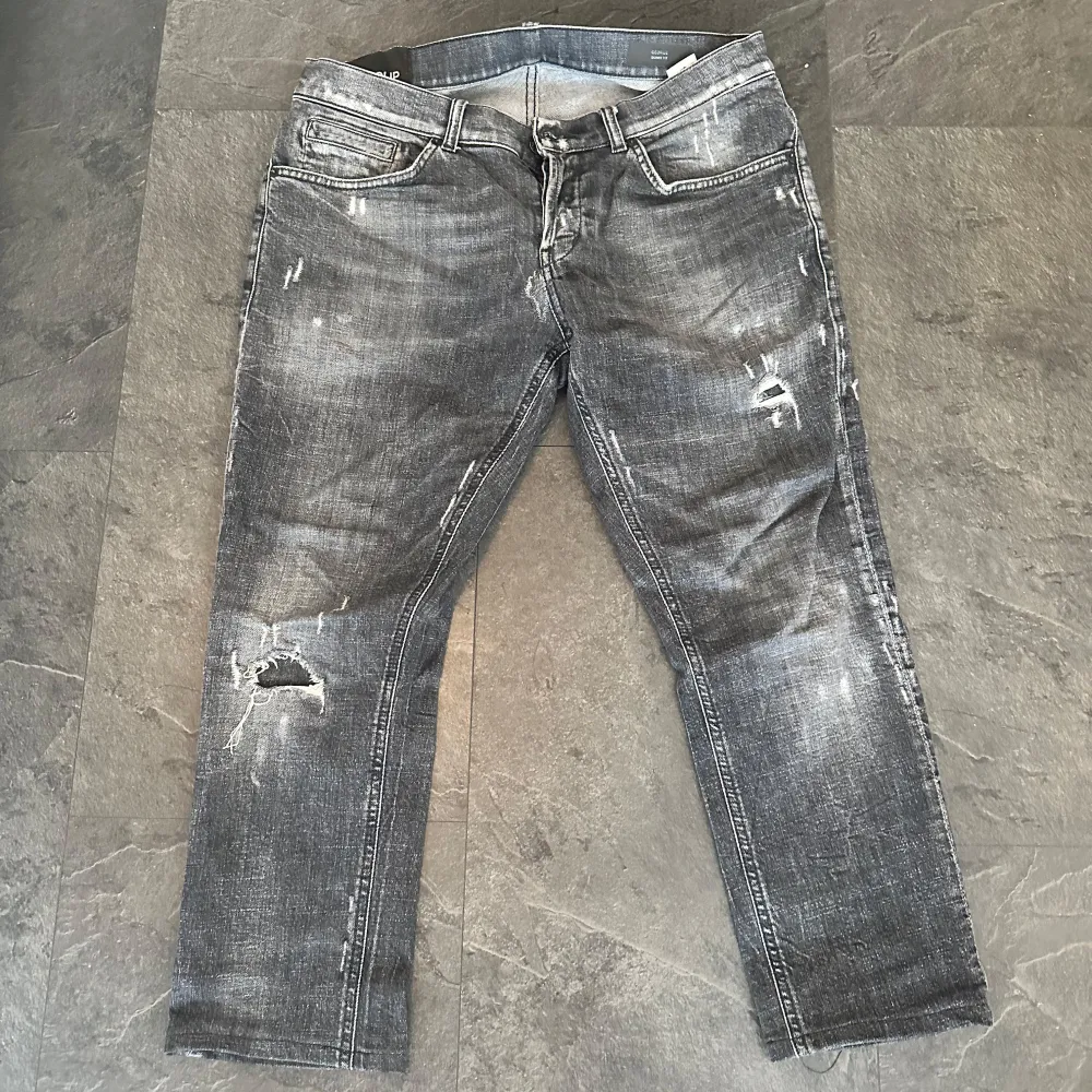 Snygga grå jeans från Dondup med slitna detaljer och en snygg tvättad look. De har en klassisk femficksdesign och knappgylf. Perfekta för en avslappnad stil. Väldigt bra skick, endast nedkortade ben, ca 90cm. Farkut & Housut.