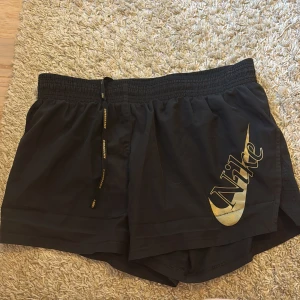 Svarta shorts från Nike - Snygga svarta shorts från Nike med elastisk midja och dragsko. Stort Nike-logotyp tryck på sidan. Perfekta för sport och fritid.
