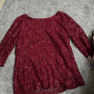 Vinröd spetsblus från SOLO - Säljer en elegant vinröd spetsblus från SOLO. Blusen har trekvartsärmar och ett vackert blommigt mönster. Perfekt för en stilfull look. 🌹