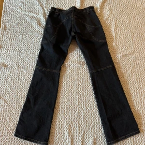 Marinblå jeans med cool design  - Snygga marinblå jeans med cool design i form av olika sömmar. Byxorna har en klassisk design med en rak passform och är perfekta för en avslappnad stil. De har en knapp och dragkedja framtill. Fler bilder kan skickas vid intresse