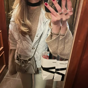 Ljusblå quiltad jacka - Säljer en ljusblå quiltad jacka med knappar framtill. Jackan har en stilren design med långa ärmar och en normal passform. Perfekt för kyligare dagar när du vill hålla stilen.