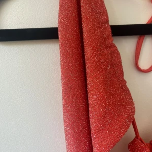 Coral glittrig klänning - Snygg coral glittrig klänning med snörning i ryggen. Perfekt för en festlig kväll. Klänningen har en smickrande passform och är tillverkad i ett glittrande material. 