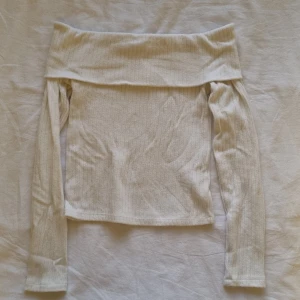 Vit offshoulder topp - Säljer en stilren vit offshoulder topp med långa ärmar. Toppen är ribbad och har en elegant design som passar perfekt för olika tillfällen. Perfekt för dig som vill ha en trendig och bekväm stil.