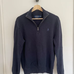 Mörkblå tröja från Polo Ralph Lauren - Säljer en stilren mörkblå tröja från Polo Ralph Lauren i mjuk pima bomull. Tröjan har en dragkedja vid halsen och långa ärmar. Perfekt för en avslappnad men snygg look. Den är lite liten i storleken så sitter mer som en S.
