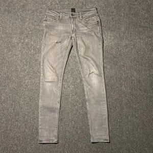 Gråa jeans med slitningar från Tiger of Sweden  - Gråa tiger of Sweden jeans med feta slitningar | Skick 8/10 | Storlek W31 L32 men sitter som W28 L31| Komm vid intresse och tveka ej vid frågor och funderingar