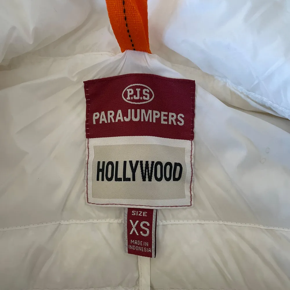 Säljer en snygg vit dunjacka från Parajumpers med dragkedja och hög krage. Jackan har ett coolt märke på ärmen och praktiska fickor med dragkedja. Perfekt för kyliga dagar!. Takit.