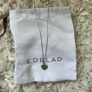 Halsband med hjärta från Edblad - Snyggt halsband från Edblad i silverfärg med ett litet hjärtformat hänge. Kedjan är tunn och stilren, perfekt för dig som gillar minimalistiska smycken med en söt touch. Levereras i originalpåse från Edblad.